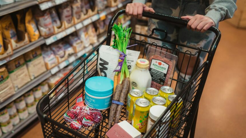 A shopper pushing a cart full of groceries down a store aisle