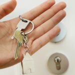 A hand holding a set of house keys at a front door
