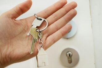 A hand holding a set of house keys at a front door