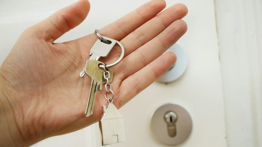 A hand holding a set of house keys at a front door