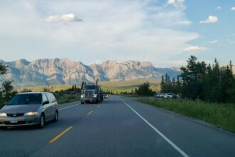 Cars and a truck on a highway near Jasper with mountains behind