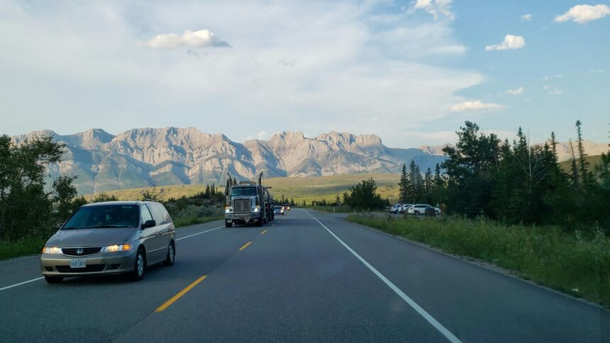 Cars and a truck on a highway near Jasper with mountains behind