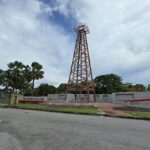 A historic wooden oil derrick standing among trees
