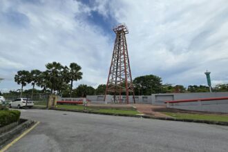 A historic wooden oil derrick standing among trees