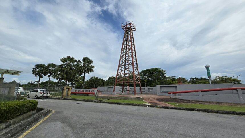 A historic wooden oil derrick standing among trees
