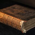 A worn leather bound ledger closed on a wooden surface