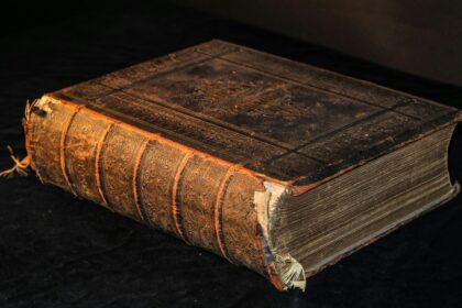 A worn leather bound ledger closed on a wooden surface