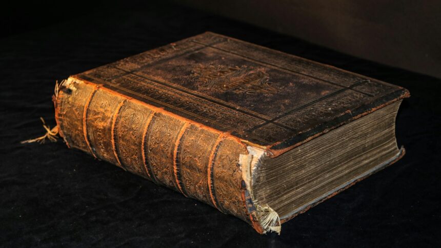 A worn leather bound ledger closed on a wooden surface