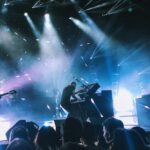 A band performing on a lit stage in front of an audience