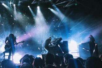 A band performing on a lit stage in front of an audience