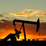 An oil pumpjack silhouetted against an orange sunset