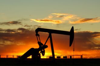An oil pumpjack silhouetted against an orange sunset