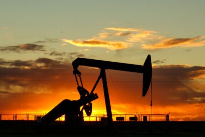 An oil pumpjack silhouetted against an orange sunset