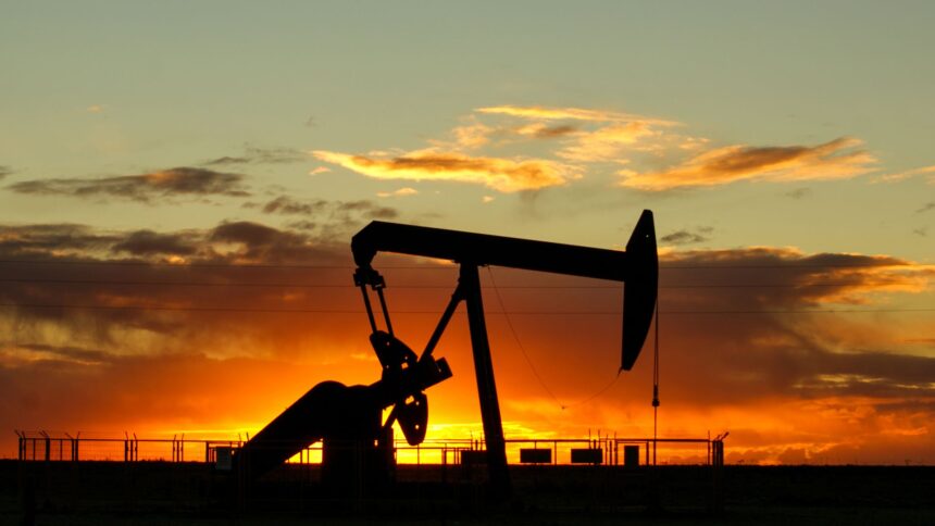 An oil pumpjack silhouetted against an orange sunset