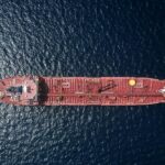 An aerial view of a red oil tanker crossing open water
