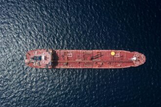 An aerial view of a red oil tanker crossing open water