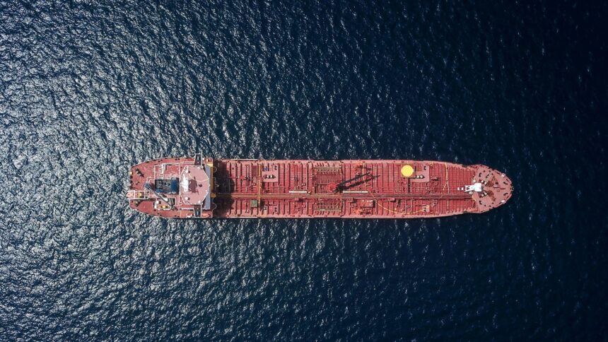 An aerial view of a red oil tanker crossing open water