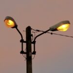 Two old street lamps glowing against an evening sky