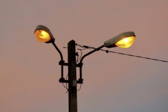 Two old street lamps glowing against an evening sky