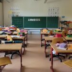 Empty classroom with rows of wooden desks facing a blackboard