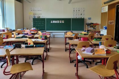 Empty classroom with rows of wooden desks facing a blackboard
