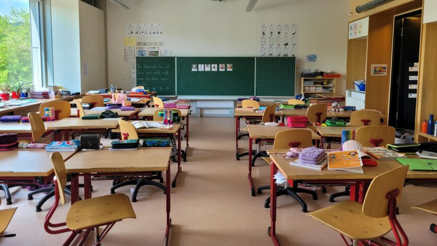 Empty classroom with rows of wooden desks facing a blackboard