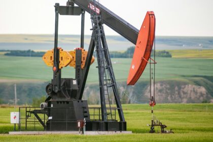 An oil pumpjack in a green field in central Alberta