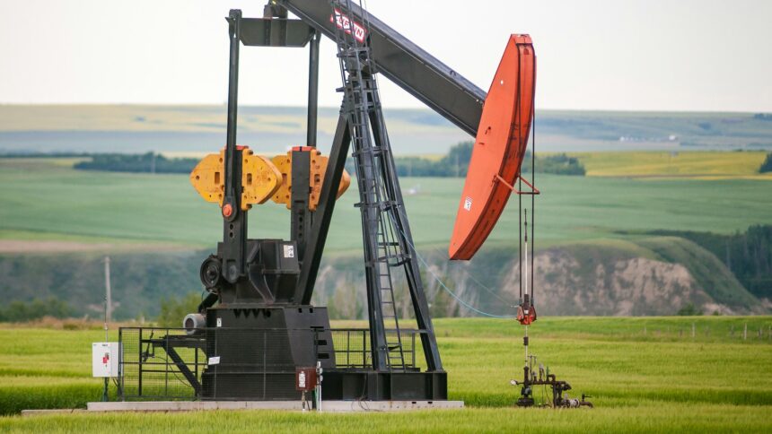 An oil pumpjack in a green field in central Alberta