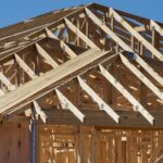 Wooden roof trusses on a house under construction against a blue sky