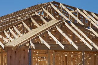 Wooden roof trusses on a house under construction against a blue sky