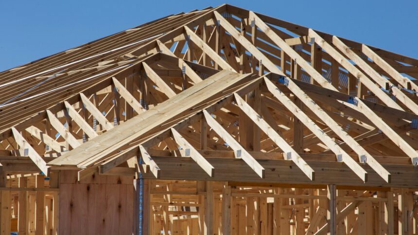 Wooden roof trusses on a house under construction against a blue sky