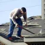 A worker removing old shingles from a residential roof