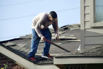 A worker removing old shingles from a residential roof