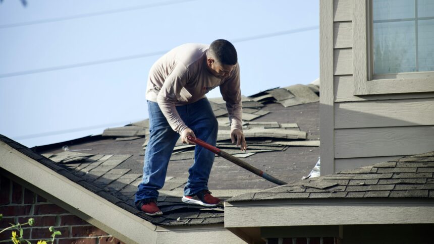 A worker removing old shingles from a residential roof