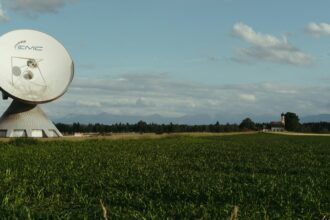 A satellite dish mounted beside a field in open farm country