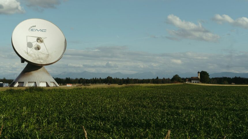 A satellite dish mounted beside a field in open farm country