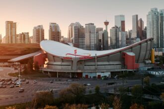 Aerial view of the Scotiabank Saddledome curved roof with the Calgary skyline behind
