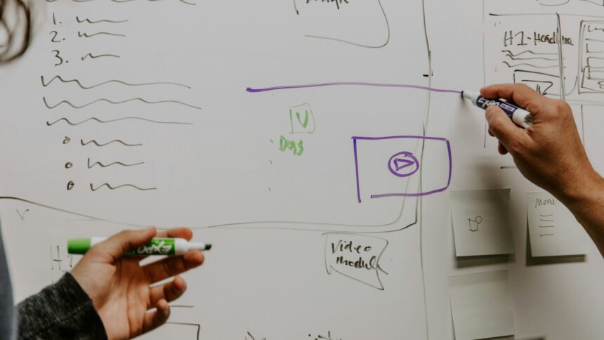Two people working through a plan on a whiteboard in an office