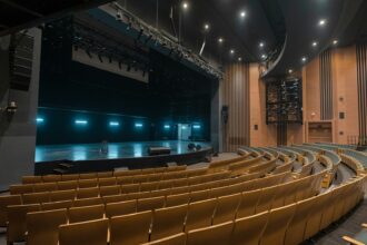 An empty theatre auditorium with rows of seats facing a stage