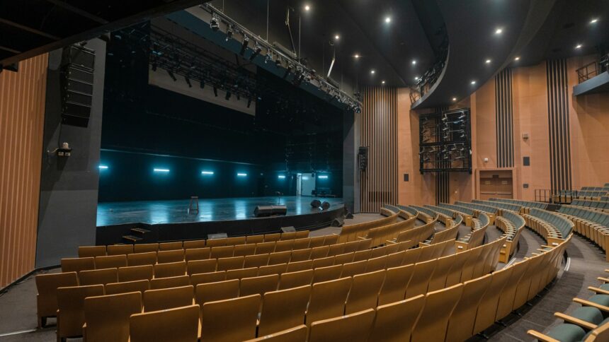 An empty theatre auditorium with rows of seats facing a stage