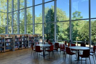 A library interior with tall windows and long study tables