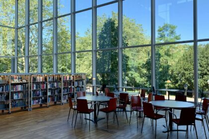 A library interior with tall windows and long study tables