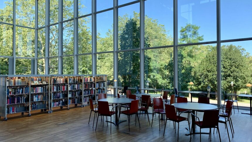 A library interior with tall windows and long study tables