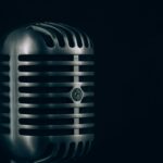 A vintage chrome microphone against a dark background