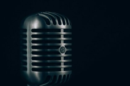 A vintage chrome microphone against a dark background