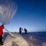 A weather balloon carrying an instrument package being launched by hand