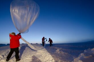 A weather balloon carrying an instrument package being launched by hand