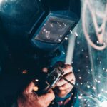 A welder in a protective mask working under a shower of sparks