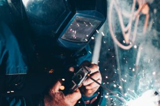 A welder in a protective mask working under a shower of sparks