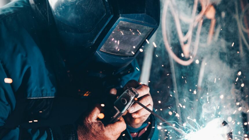 A welder in a protective mask working under a shower of sparks